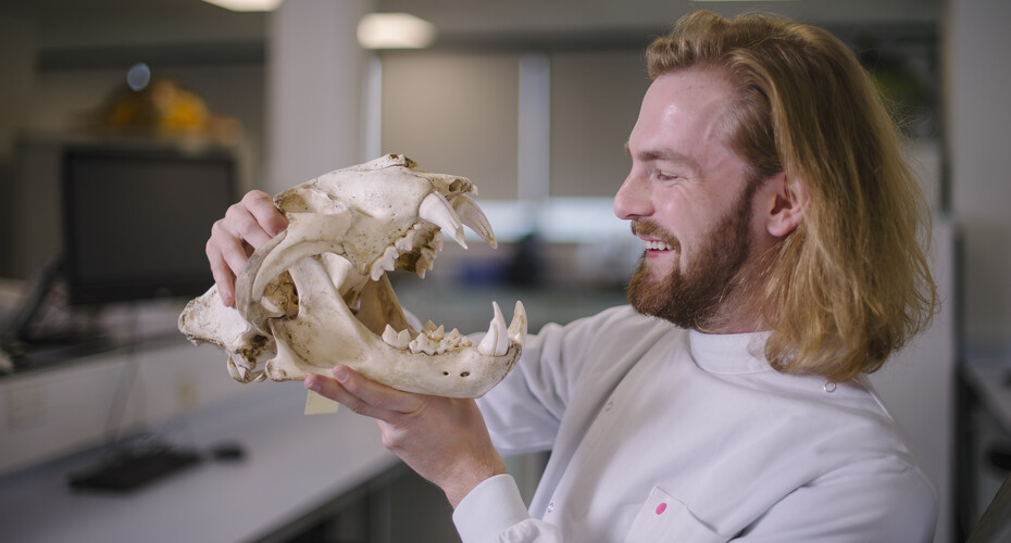 A student grinning at an animal skull
