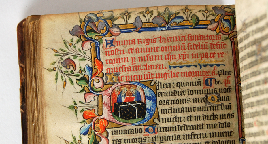Close up of a page from an ancient book with text in bright colours and a decorative gold and coloured border