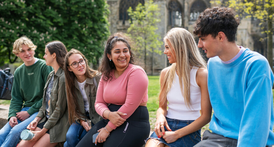 A group of students sitting on the cathedral green wall