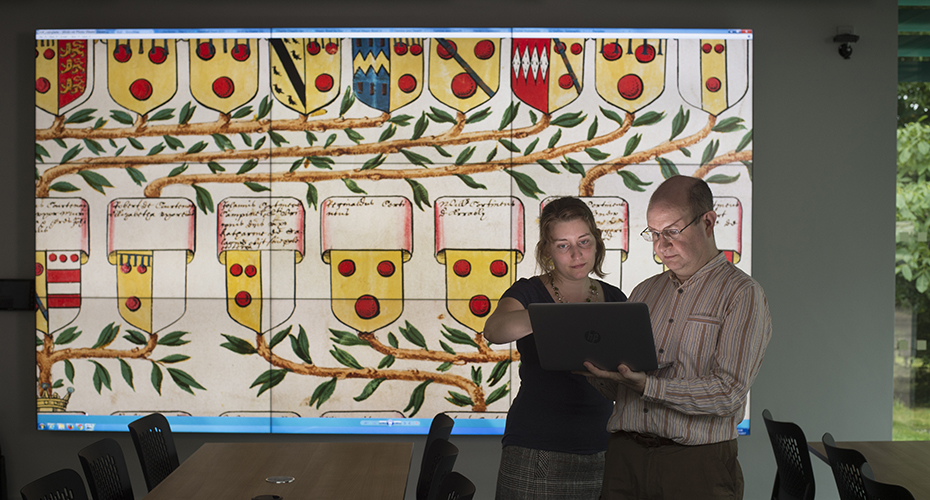 Looking at a laptop in front of the Powderham scroll on the video wall