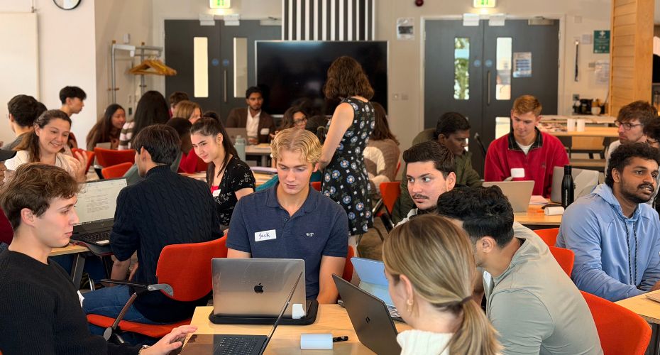 Group of students sat at tables working on laptops
