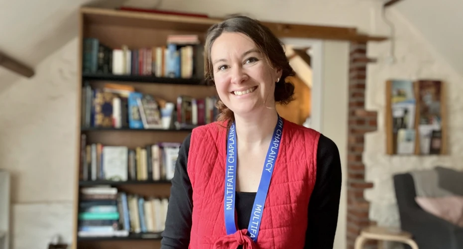 head and shoulders image of Gorgi Pritchard who is stood in front of a doorway and bookcase