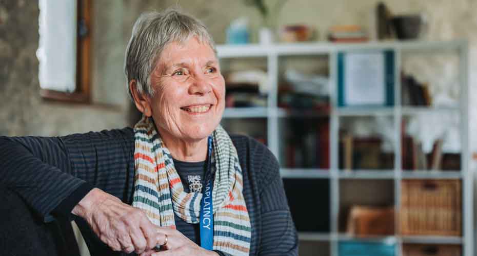 Jan Webb wearing a stripy scarf smiling and looking off to the distance