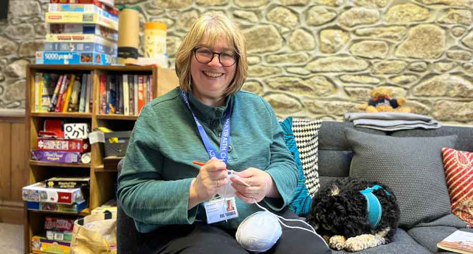 Mary Stevenson smiling to camera whilst knitting