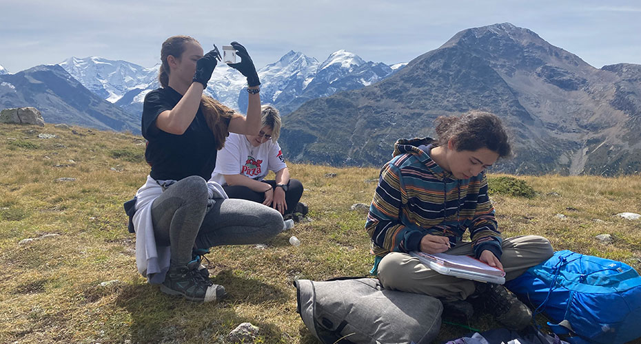 Students doing field work in front of swiss mountains
