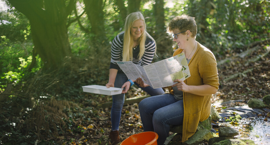Two students in woodland, identifying wildlife with a key