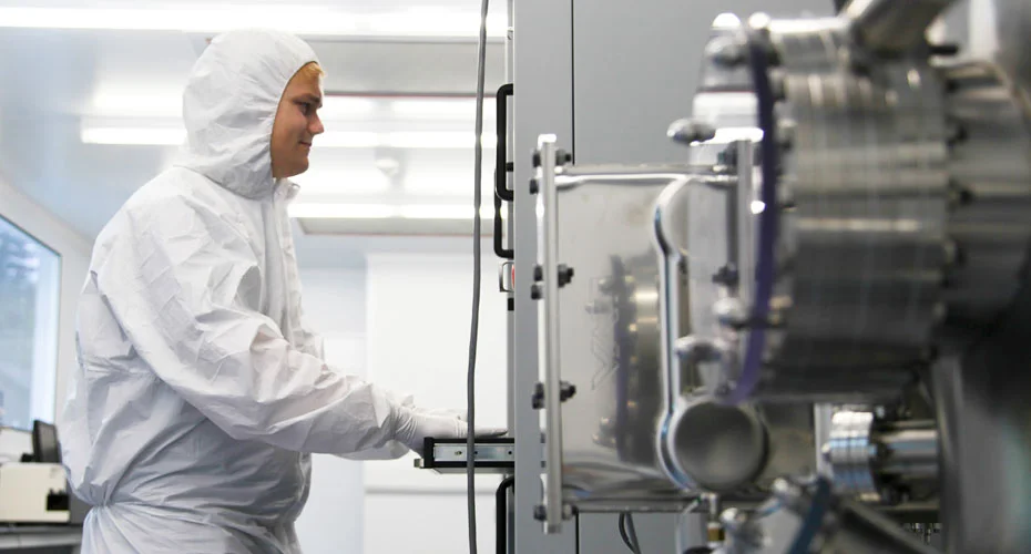 A researcher wearing a hazmat suit using the Kurt J Lesker evaporation system