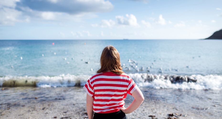 Student in striped tshirt looking out to sea