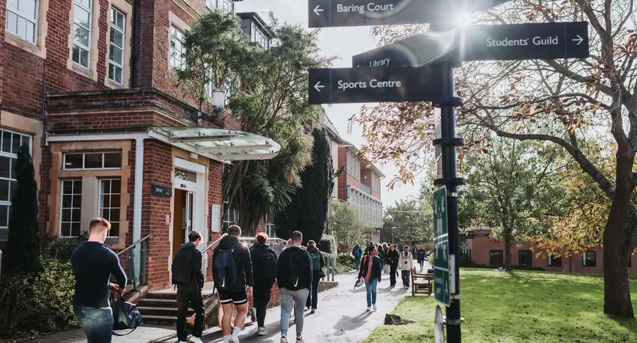Students walking past St Luke's Library (Haighton) adjacent to the main quad during autumn.