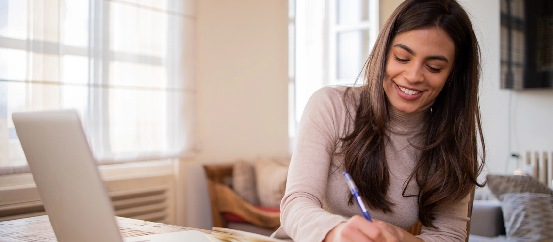 A student studying online using a laptop and notebook.