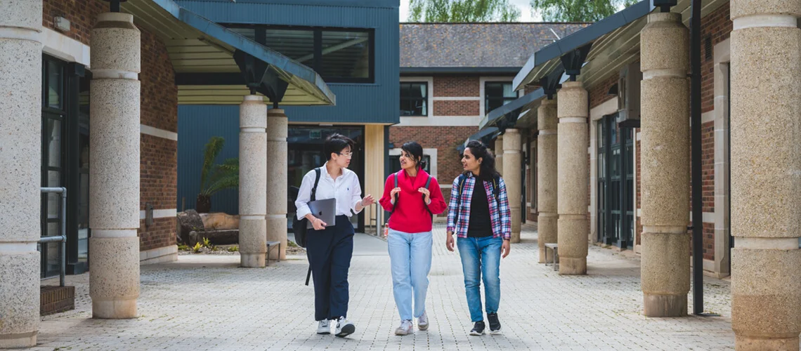 Business School students walking together outside of Streatham Court on Streatham Campus.
