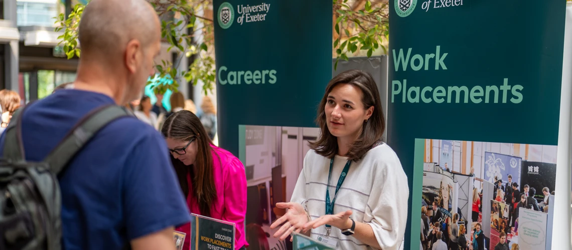 Prospective Master's students and Exeter staff talking at a stand during a postgraduate open day.