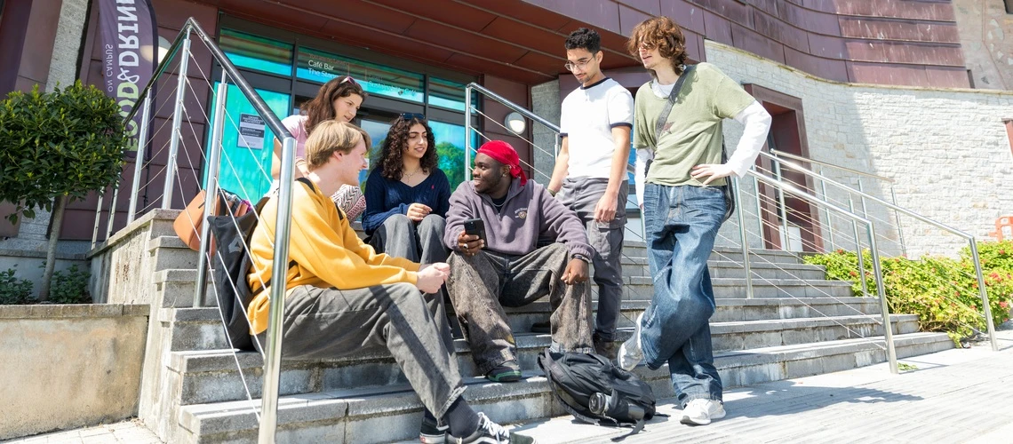 A group of students talking together on a beautiful day on our Penryn Campus in Cornwall.