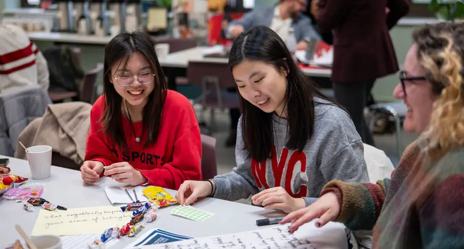 International students sitting around a table with paper and pens and sweets on working together.