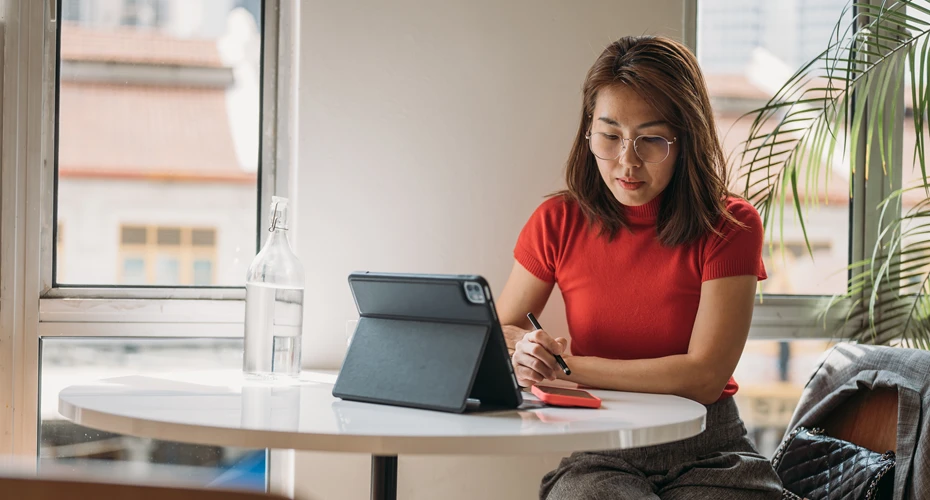 An online MBA student studying with a tablet at a desk.