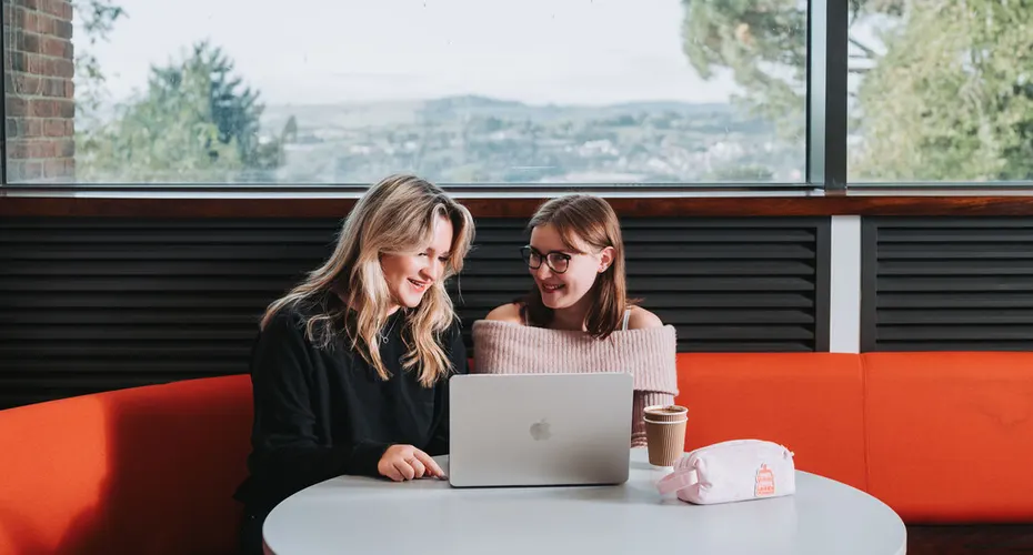 Two students sat talking, socialising, and studying together in the Physics Building on campus.