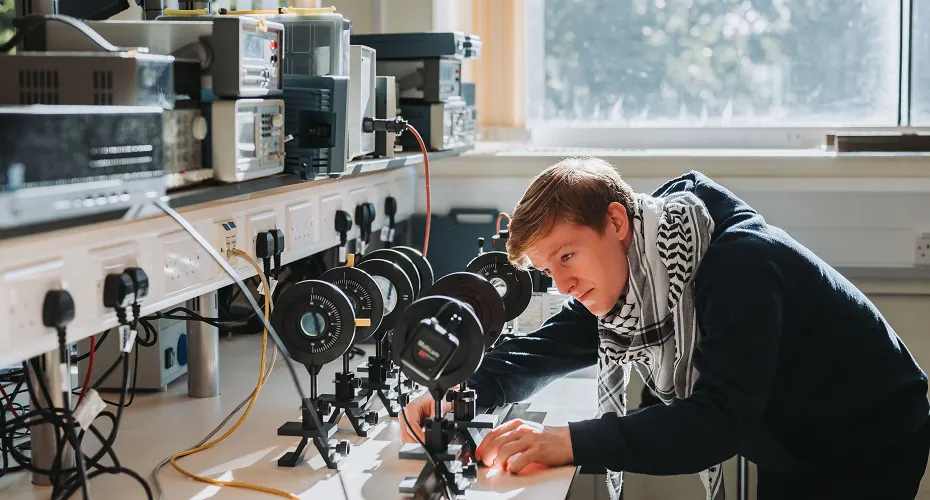 A Physics and Astronomy student working and studying in a lab on campus.