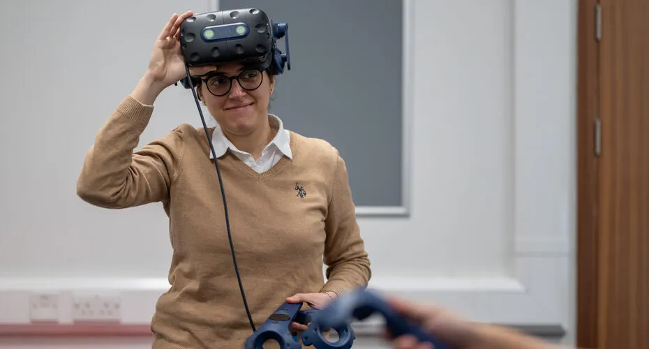 Student smiling wearing a VR headset in an engineering lab.