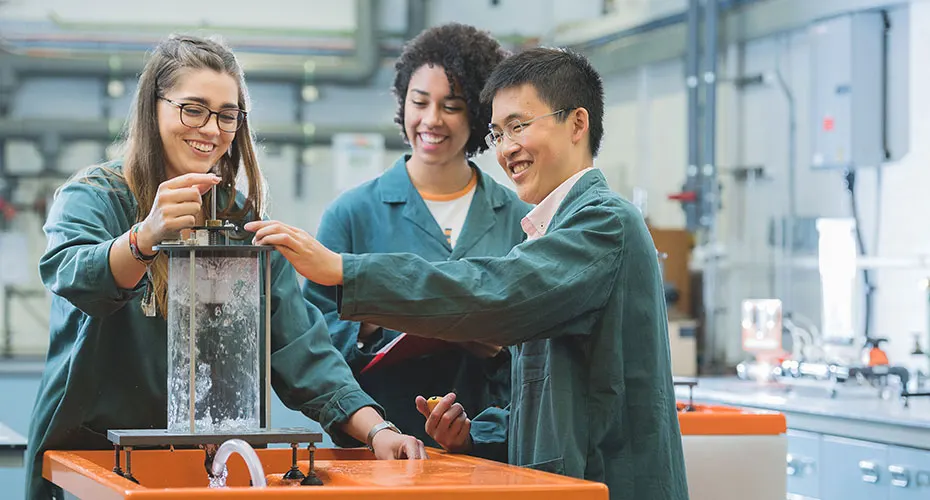 Three students experimenting with water in an engineering lab.
