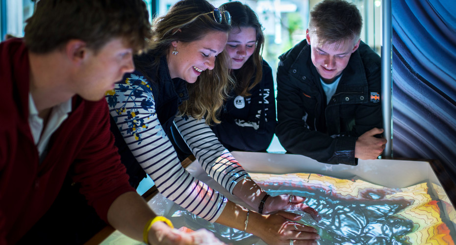 A group of students looking at a light up table displaying a map