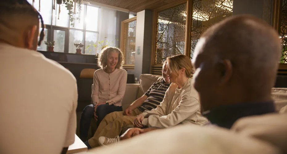 Group of people sitting on sofas chatting together and smiling.