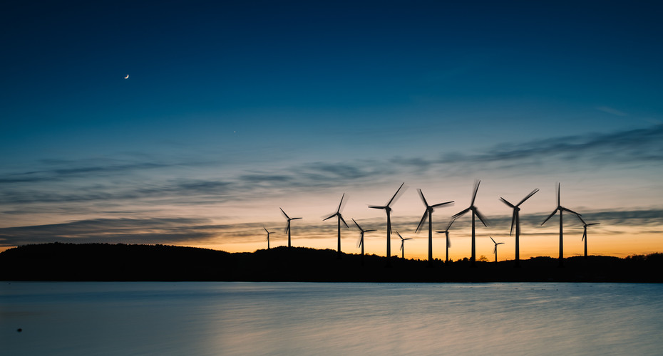Offshore wind turbines silhouetted against a sunset