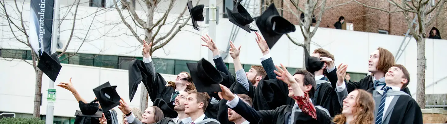 Students at winter graduation throwing their mortar boards in the air.