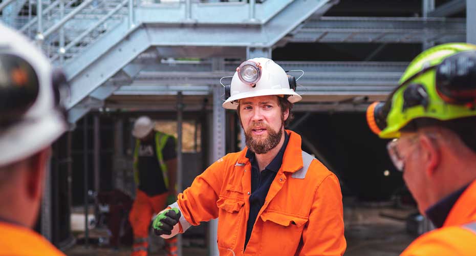 A man in a hardhat and orange jacket.