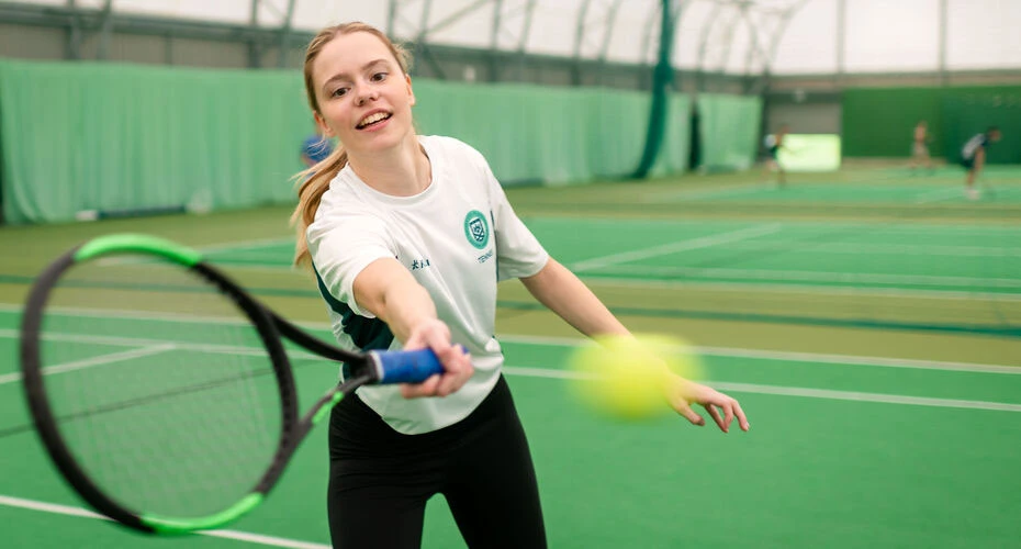 A student playing tennis at the Tennis Centre