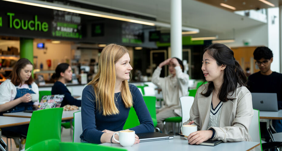 Student enjoying a coffee in a cafe on campus