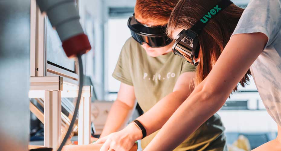 Students wearing googles in a lab looking at a microscope.