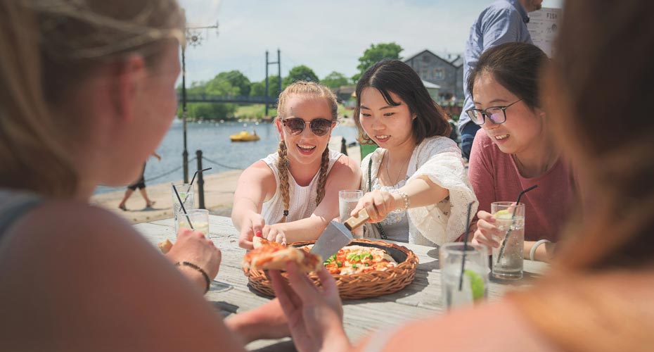 Students eating pizza by the Quay