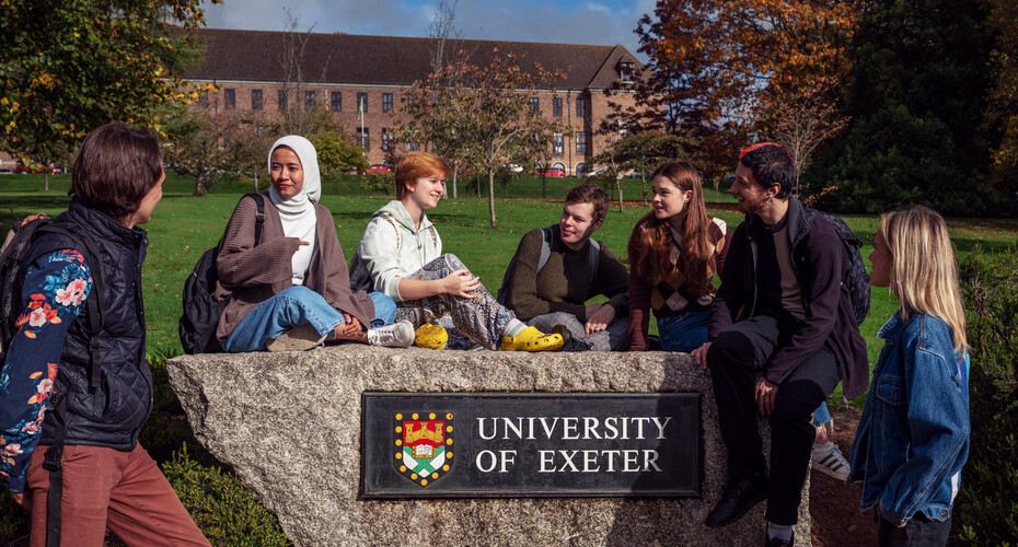 A group of students sitting on the University of Exeter rock at Streatham Campus
