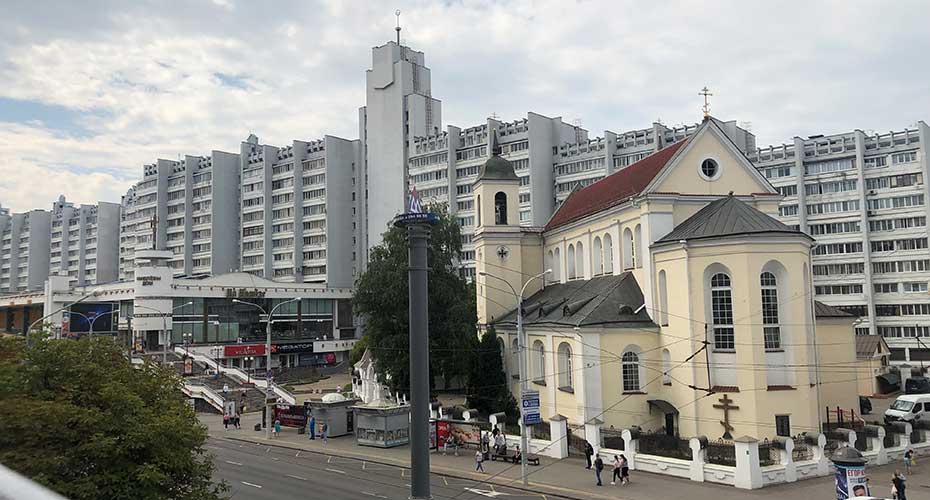 A church in Minsk  surrounded by tall city buildings, showcasing a blend of historic and modern architecture in an urban setting.