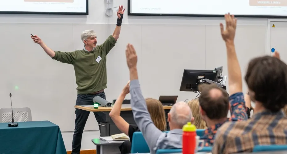 Ben Groom, raises his hands to engage the audience at the LEEP@10 event.