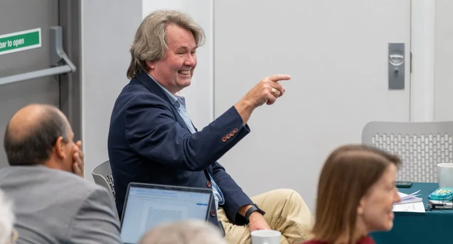 Professor Ian Bateman in a suit, gesturing towards a group of attendees at the LEEP@10 event.