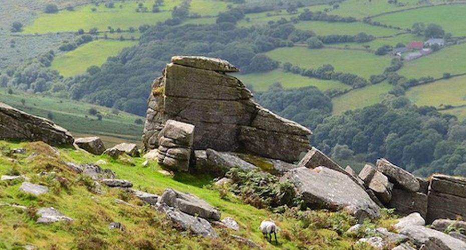 A scenic countryside vista seen from a rocky hillside, showcasing the natural beauty of the landscape.