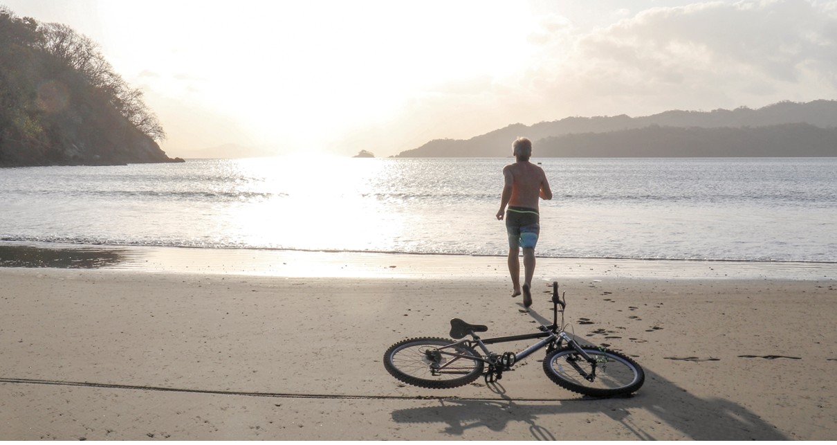 A man running towards the sea behind a bike