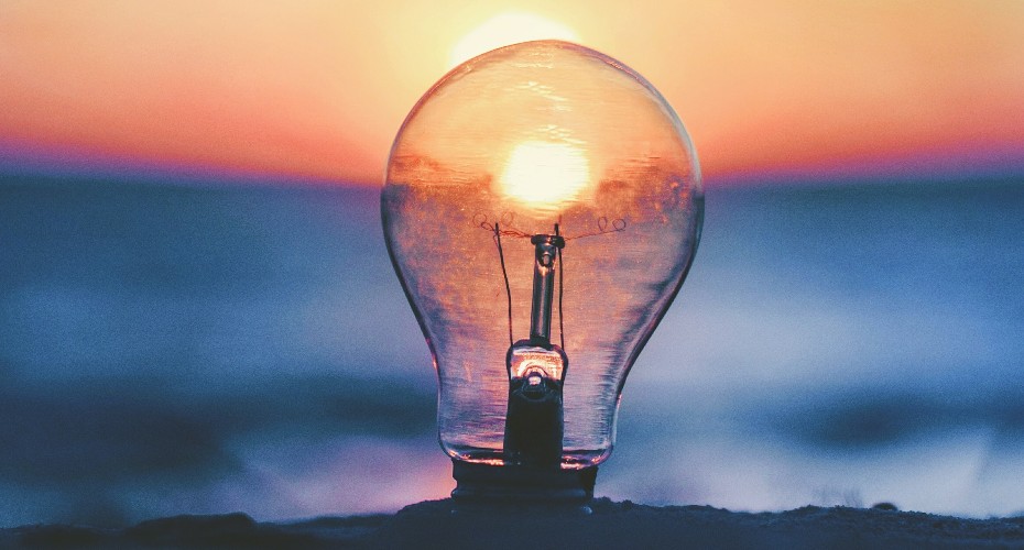 light bulb against ocean seaside sunset