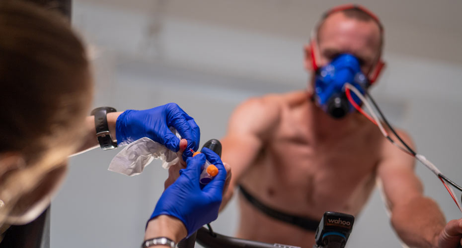 A man on an exercisie bike having some blood taken for an experiment