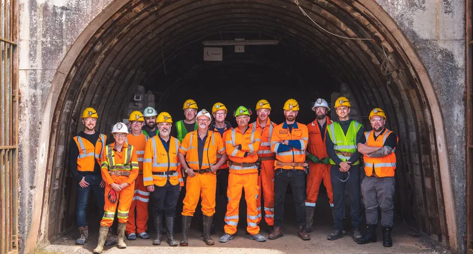 Group of students on a mining field trip, standing outside the mine all dressed in mining gear, for a group photo.