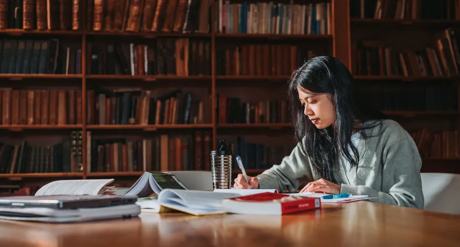 An English and Creative Writing student studying in the Lopes Hall library on Streatham Campus.