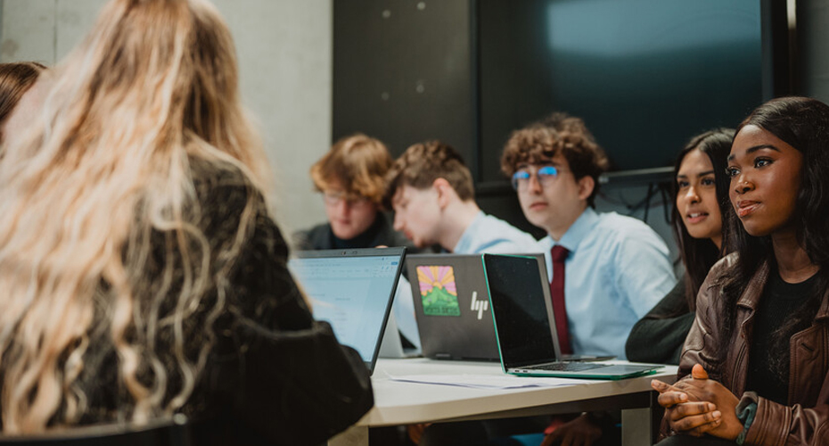 students sat around laptops talking