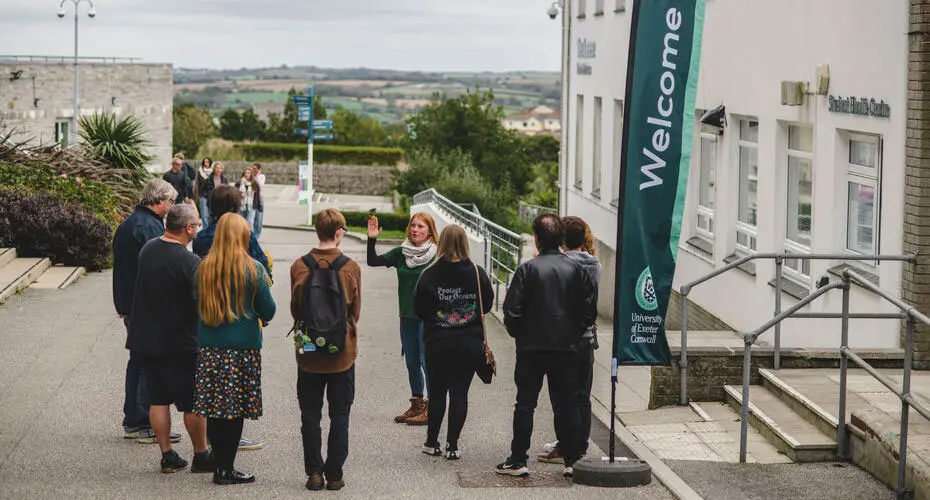 A group of students standing by a flag that says welcome.