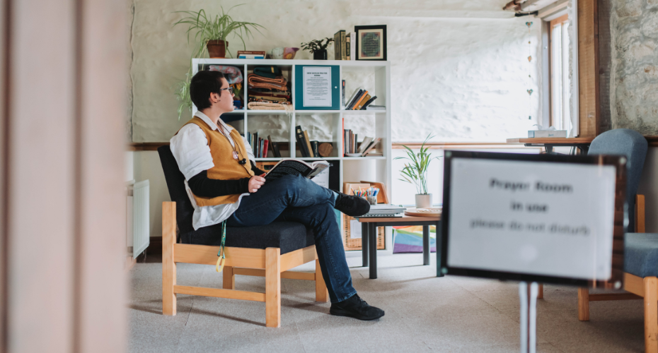 student sitting with book in prayer room