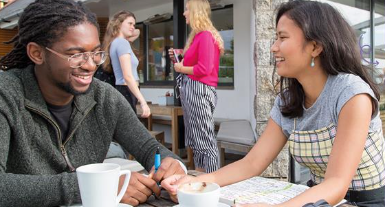 Student outside a cafe laughing and studying