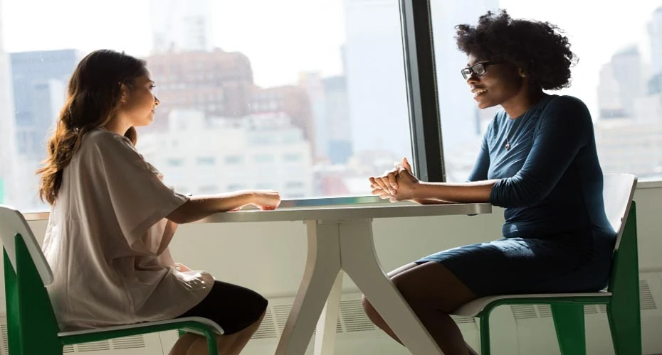 Two women sat at table having a conversation