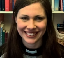 Photo of Hannah Alderson, Anglican Chaplain with an office filing shelf behind her