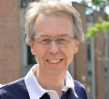 Picture focussing on Simon Taylor with a building on campus in the background