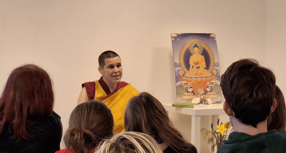 Image of Buddhist monk delivering a talk in front of a shrine